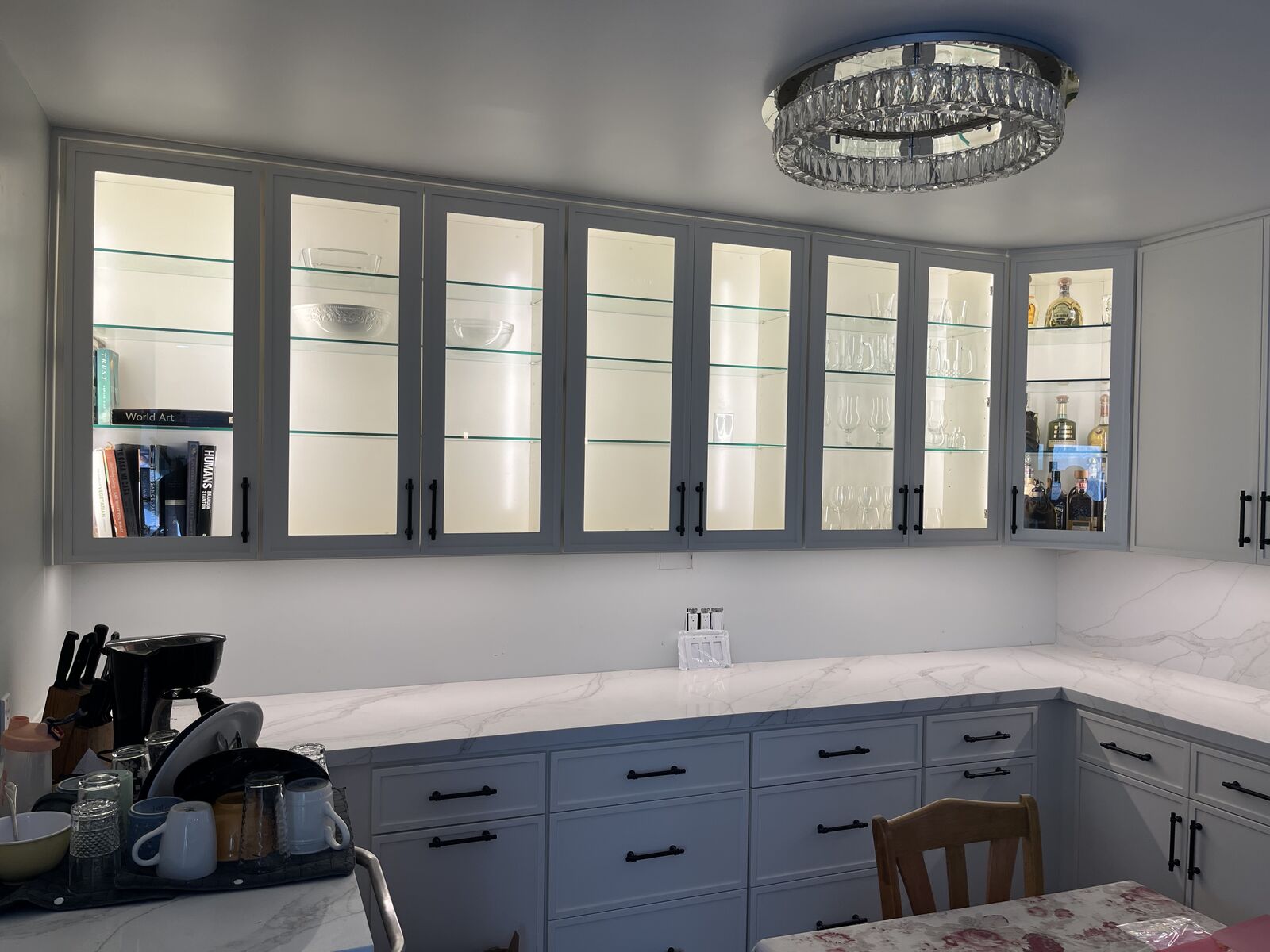 Kitchen with lighted glass cabinets and a crystal ceiling fixture